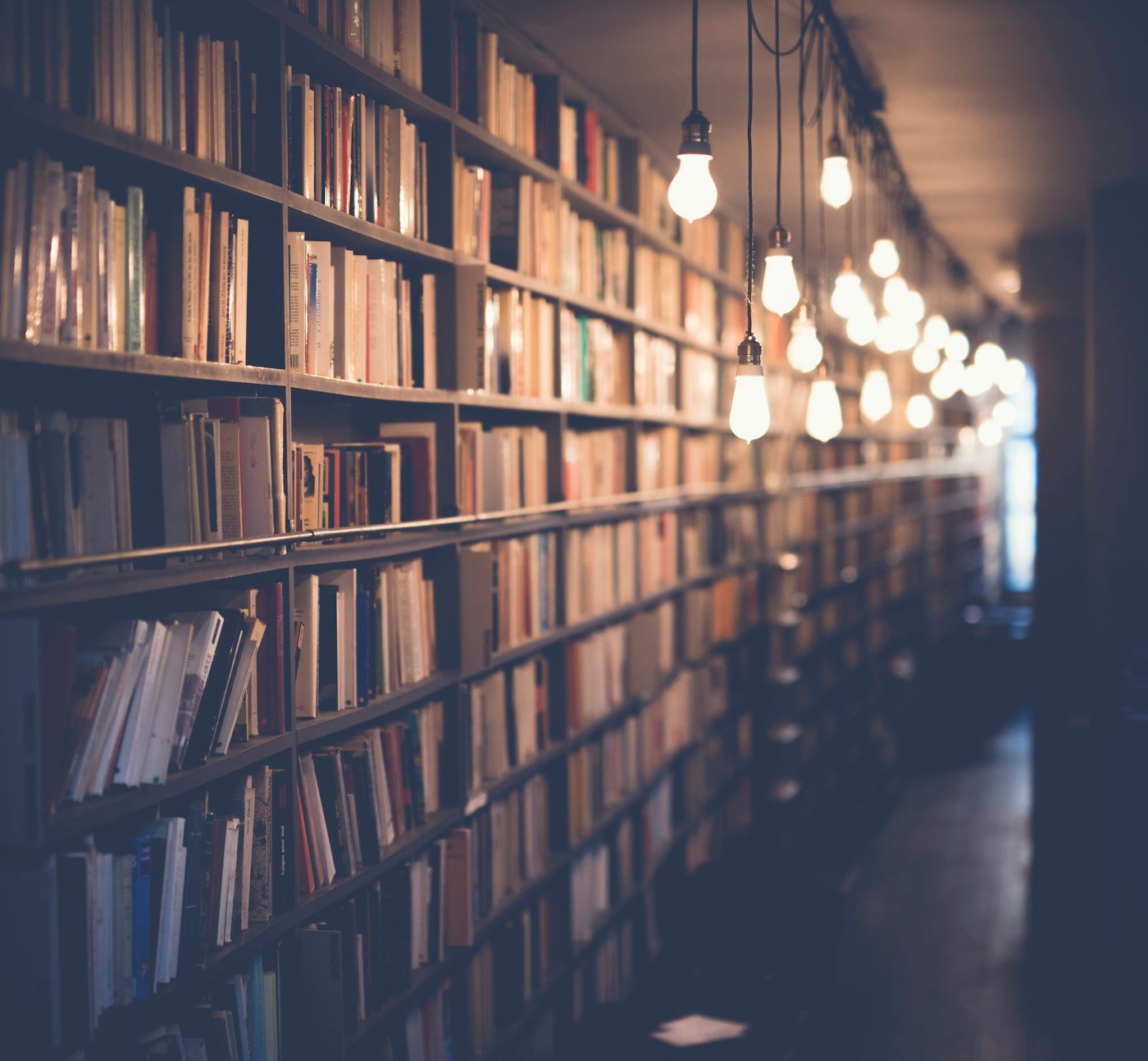 An open book beside a warm cup of coffee on a wooden desk